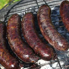 Kaszanka, tradycyjna polska kiełbasa, piecze się na grillu. Jej ciemny kolor i charakterystyczna faktura świadczą o tym, z czego jest kaszanka: z krwi, podrobów i kaszy.