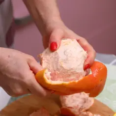 Ręce obierają grejpfruta, który jest niskokaloryczną przekąską.