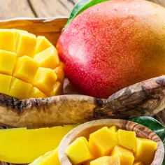 Soczyste mango w drewnianej misce, pokrojone w kostkę i w plasterkach. Idealne na zdrową przekąskę, z niskim mango kcal.