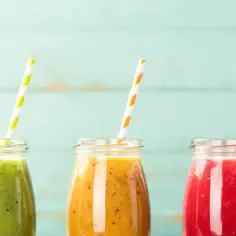 Trzy kolorowe koktajle w butelkach, idealne na dietę koktajlową. Zielony, pomarańczowy i czerwony napój z kolorowymi słomkami.