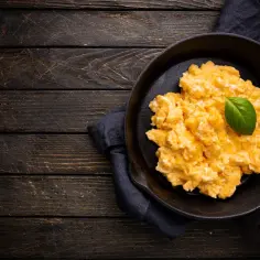Puszysta jajecznica w patelni, ozdobiona listkiem bazylii. Idealna na śniadanie, gdy liczymy jajecznica kcal.