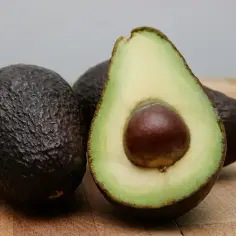 Dwa całe awokado i jedno przekrojone na pół, z widocznym pestką. Zastanawiasz się nad awokado kcal?