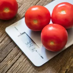 Czerwone pomidorki koktajlowe na wadze cyfrowej, która pokazuje 34g. Idealne do liczenia kcal.