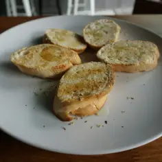 Pięć kromek bagietki czosnkowej polanych oliwą. Idealna przekąska, choć warto pamiętać o kcal.