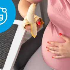 Kobieta w ciąży je banana, symbolizującego magnez.
