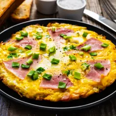 Pyszny omlet z szynką i serem, posypany szczypiorkiem. Idealny pomysł na śniadanie, jak zrobić omlet z szynką i serem.
