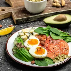 Talerz z łososiem, jajkami, awokado, serem i szpinakiem. Idealne składniki na dietę keto co jeść.