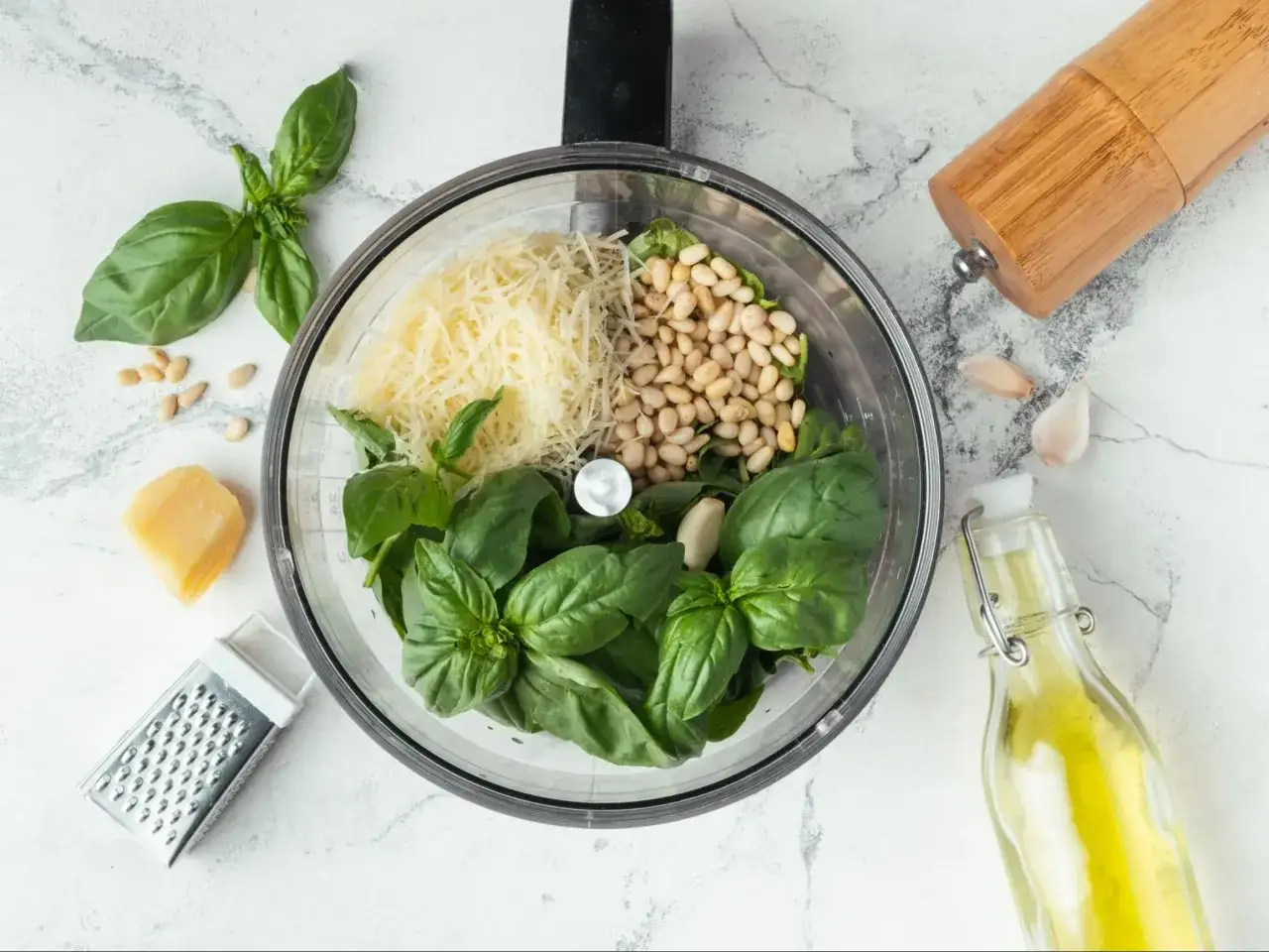 Składniki do zielonego pesto: świeża bazylia, orzeszki piniowe, starty parmezan, czosnek i oliwa.