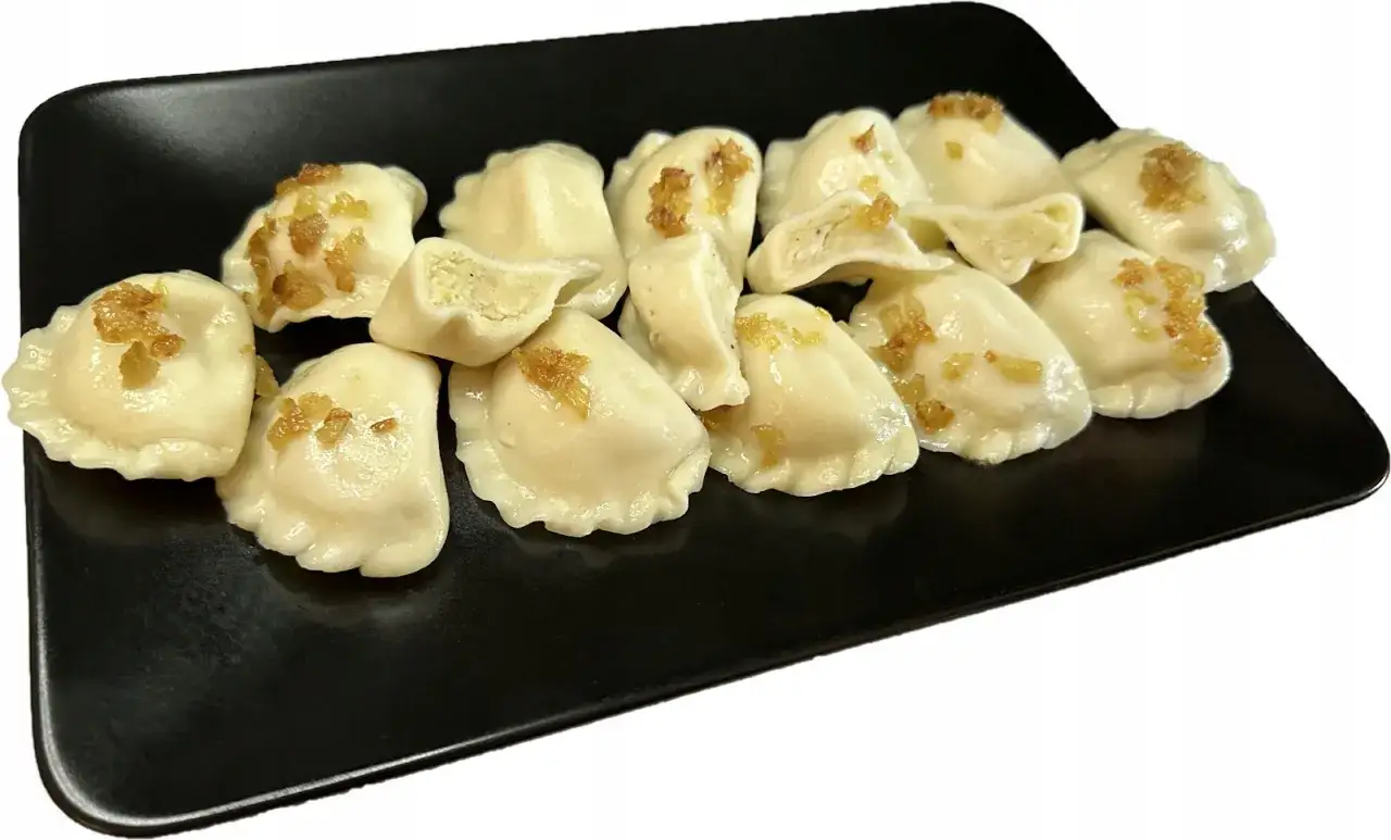 Talerz pełen pysznych pierogów ruskich, posypanych skwarkami. Idealne na obiad, choć warto pamiętać o ich pierogi ruskie kcal.
