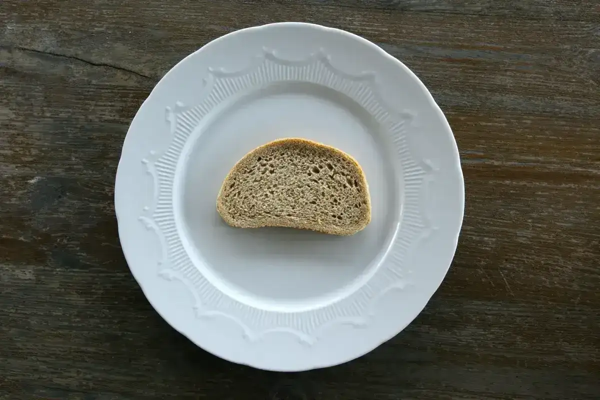 Jeden plasterek chleba żytniego na białym talerzu. Zastanawiasz się nad jego kcal?
