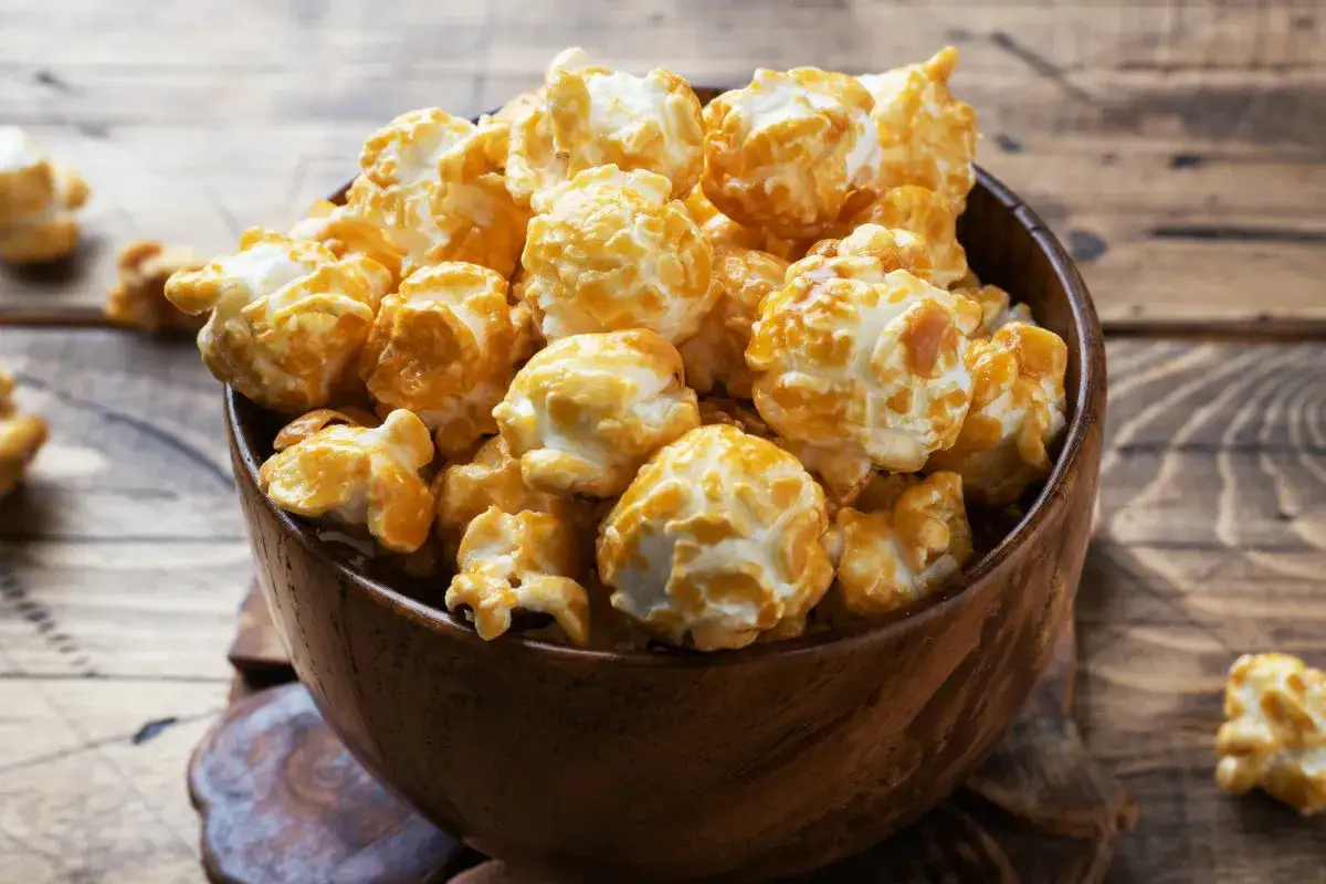Chrupiący karmelowy popcorn w drewnianej misce. Idealny przykład, jak zrobić popcorn w garnku na szybką przekąskę.