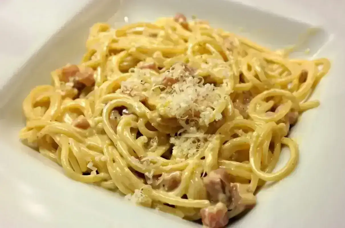 Pyszne spaghetti carbonara z kawałkami boczku i parmezanem. Idealna śmietana do carbonary to sekret tego dania.
